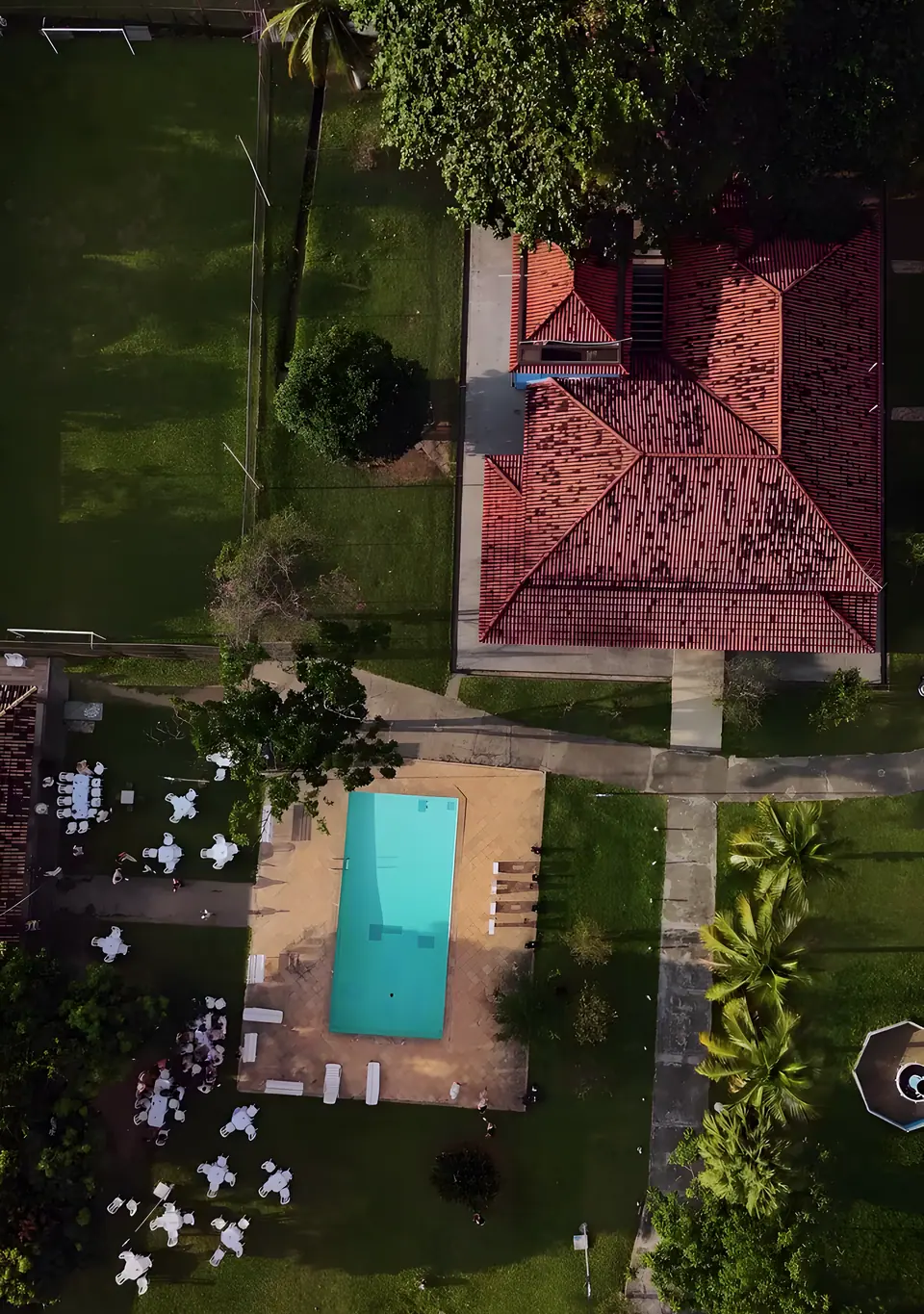 Sítio Azul visto de cima: o telhado da Casa Azul, a piscina com o deck, o gramado e as palmeiras