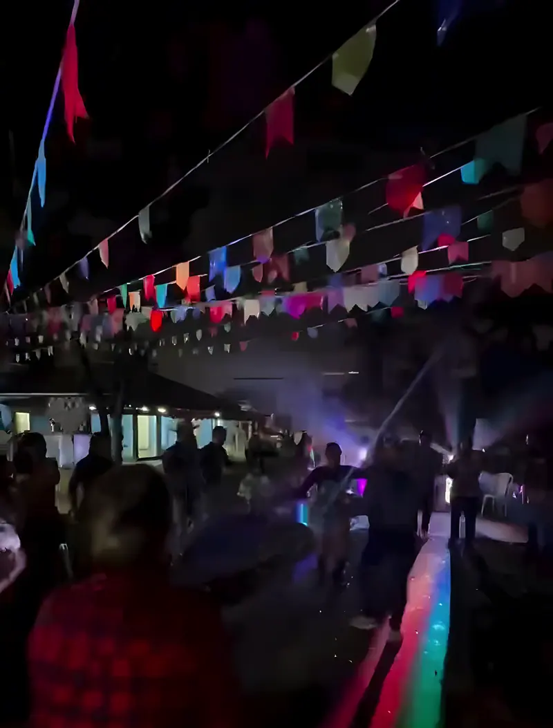 Bandeirinhas de arraiá sobre o gramado do sítio à noite, com luzes coloridas