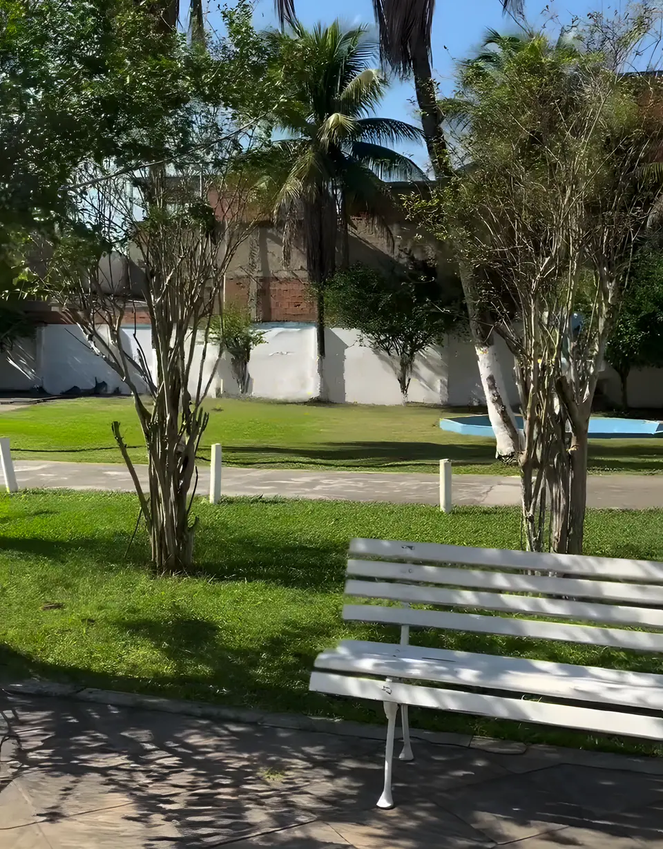 Banco branco à sombra das árvores no gramado do sítio