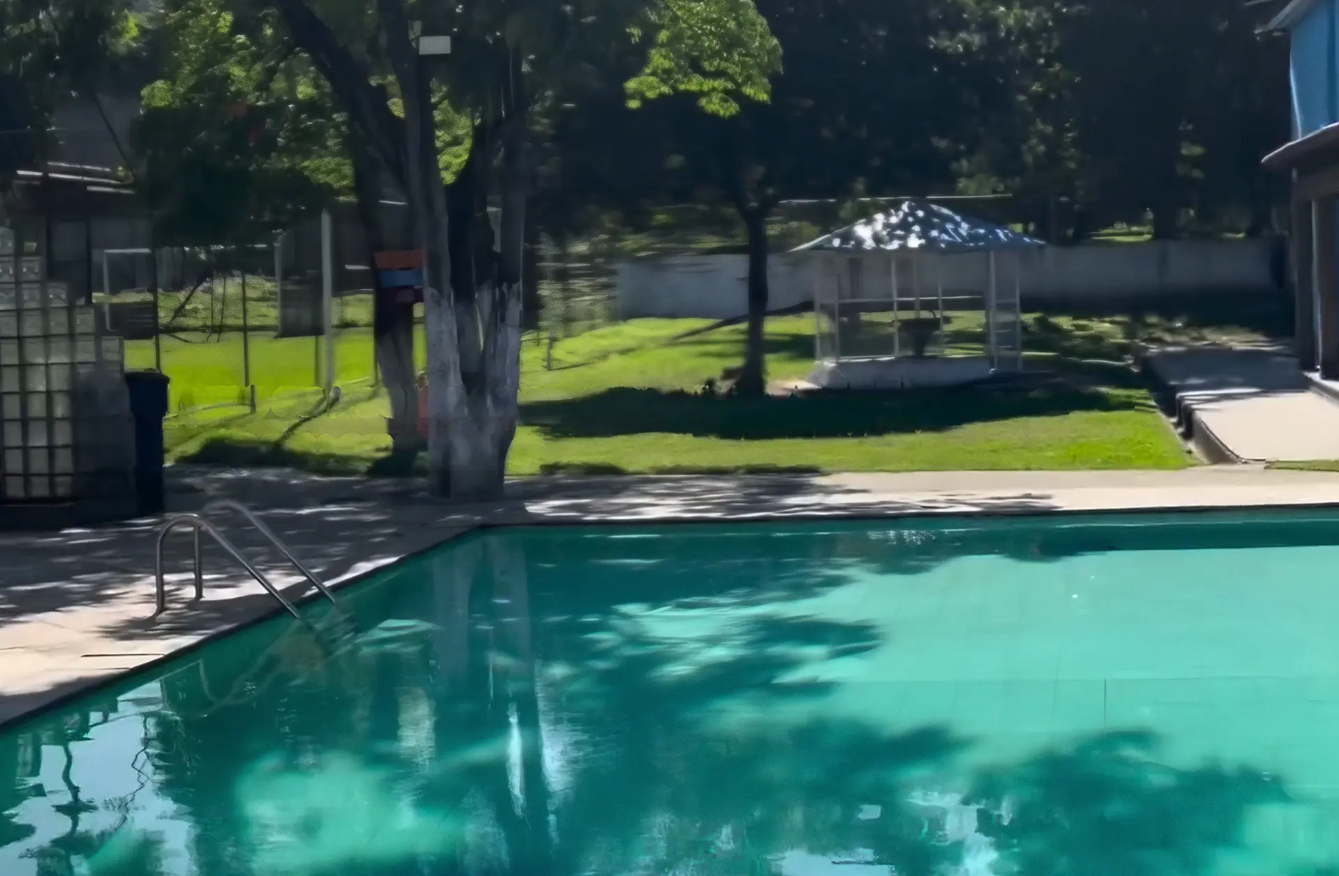 Piscina do Sítio Azul em manhã de sol, com o quiosque, o gramado e as árvores ao fundo