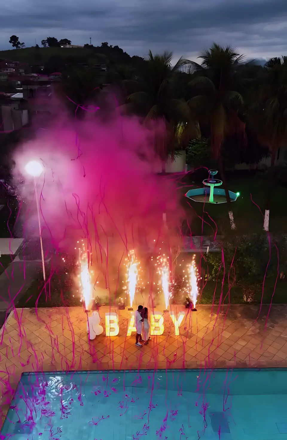 Chá revelação à noite na beira da piscina do Sítio Azul, com fumaça rosa e letreiro luminoso