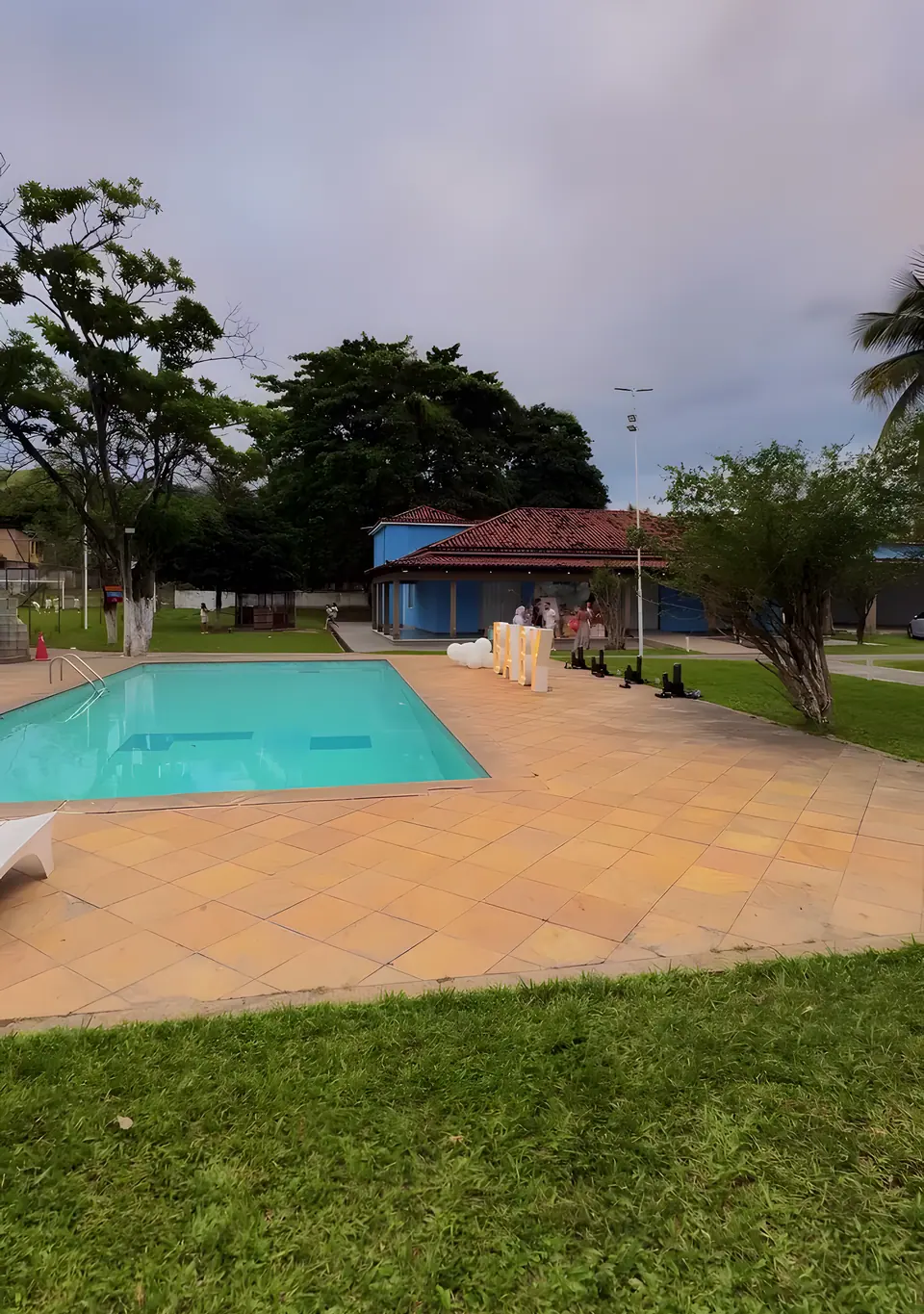 Piscina do Sítio Azul com deck de pedra e a casa ao fundo